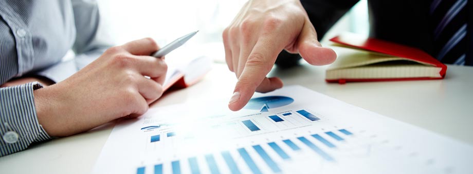 Picture of mans hands poiting at graphs on paper